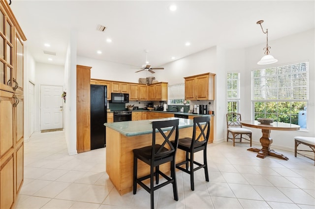 kitchen featuring a center island, light tile patterned floors, hanging light fixtures, and black appliances