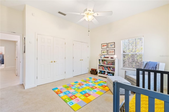 bedroom featuring ceiling fan, multiple closets, and carpet flooring