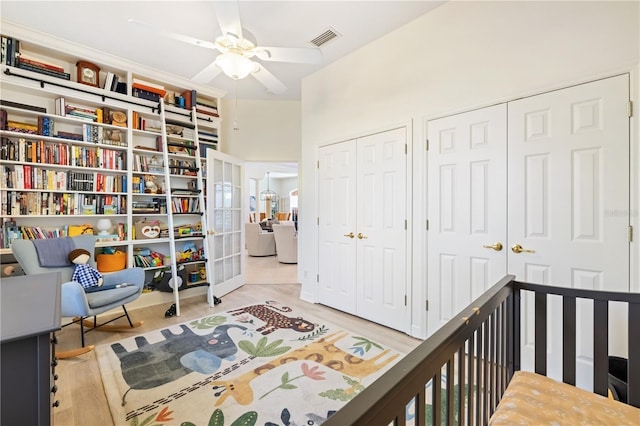 bedroom featuring multiple closets, ceiling fan, light hardwood / wood-style floors, and french doors