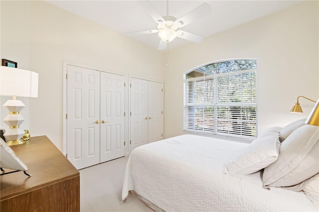 bedroom with multiple closets, ceiling fan, and light carpet