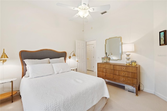 bedroom with a high ceiling, light colored carpet, and ceiling fan