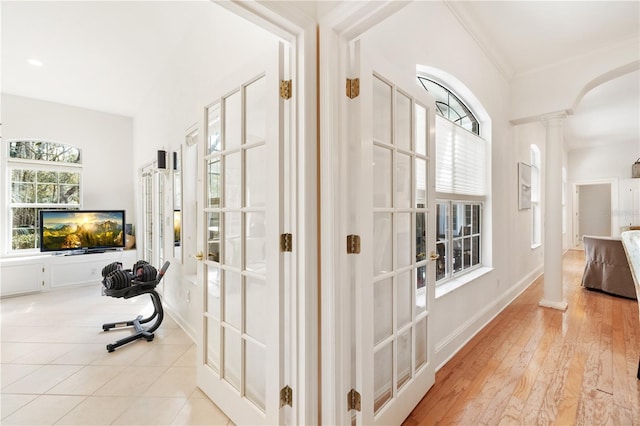 hall featuring ornate columns, crown molding, light hardwood / wood-style floors, and french doors