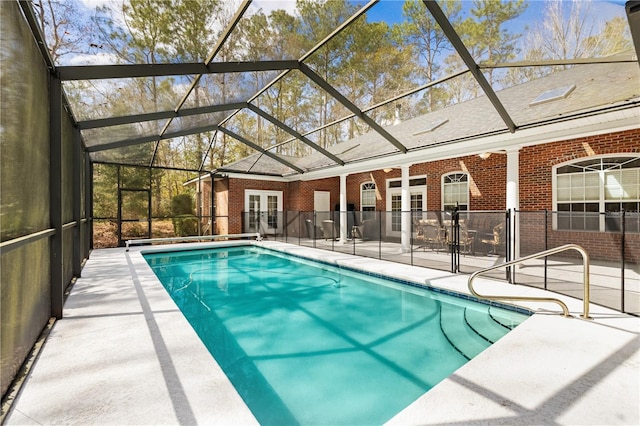 view of pool with french doors, glass enclosure, and a patio