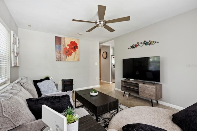 living room featuring ceiling fan and a wood stove