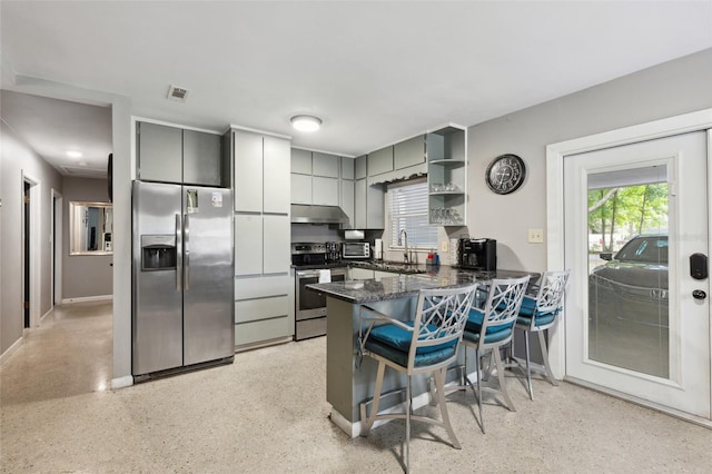 kitchen with a breakfast bar, appliances with stainless steel finishes, gray cabinets, kitchen peninsula, and a healthy amount of sunlight