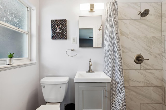 bathroom with vanity, toilet, and tiled shower