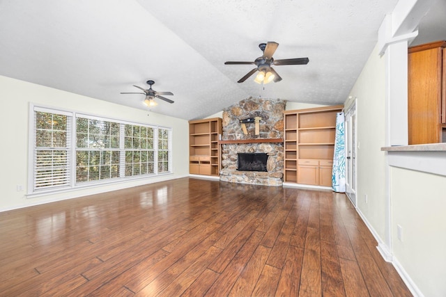 unfurnished living room featuring vaulted ceiling, a stone fireplace, wood-type flooring, ceiling fan, and a textured ceiling