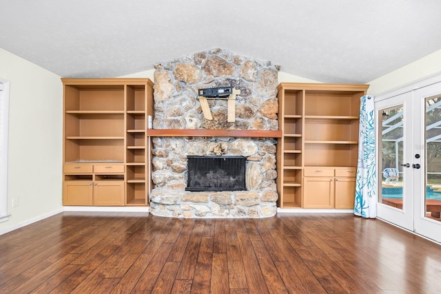 unfurnished living room with vaulted ceiling, a fireplace, dark wood-type flooring, a textured ceiling, and french doors