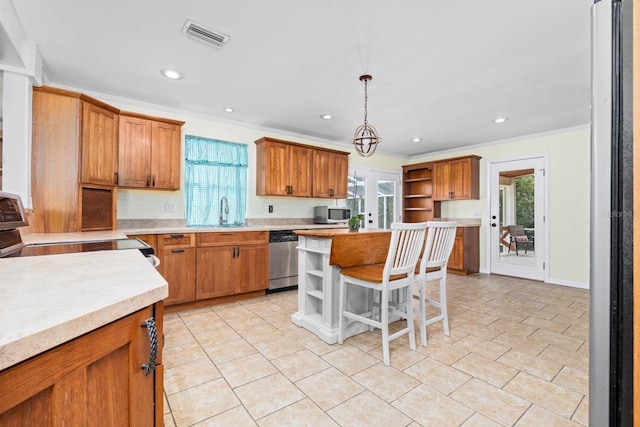 kitchen featuring appliances with stainless steel finishes, a breakfast bar, decorative light fixtures, sink, and a center island