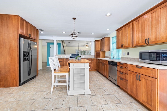 kitchen featuring a breakfast bar, sink, appliances with stainless steel finishes, a kitchen island, and pendant lighting