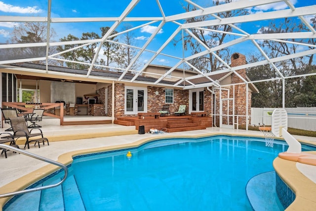 view of swimming pool with a patio area, an outdoor kitchen, and glass enclosure