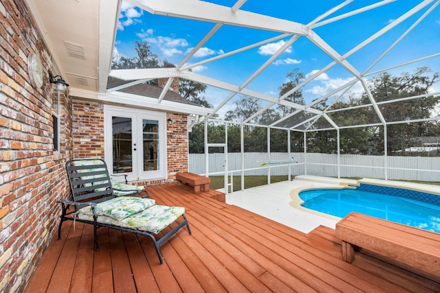 view of swimming pool with a wooden deck, french doors, and glass enclosure