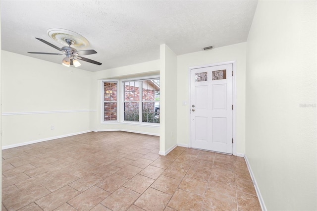 foyer entrance with ceiling fan and a textured ceiling