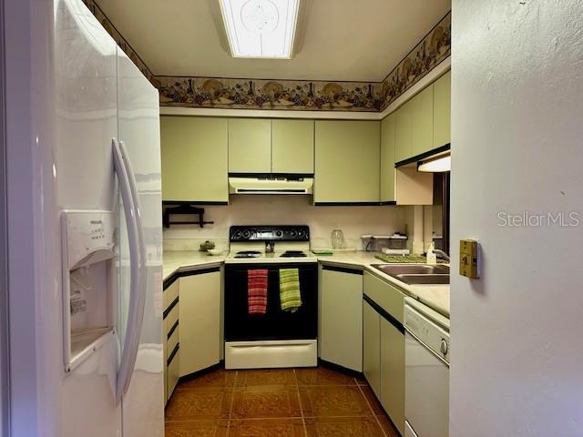 kitchen featuring sink, dark tile patterned flooring, and white appliances