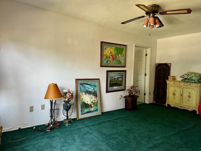 miscellaneous room featuring ceiling fan and dark carpet