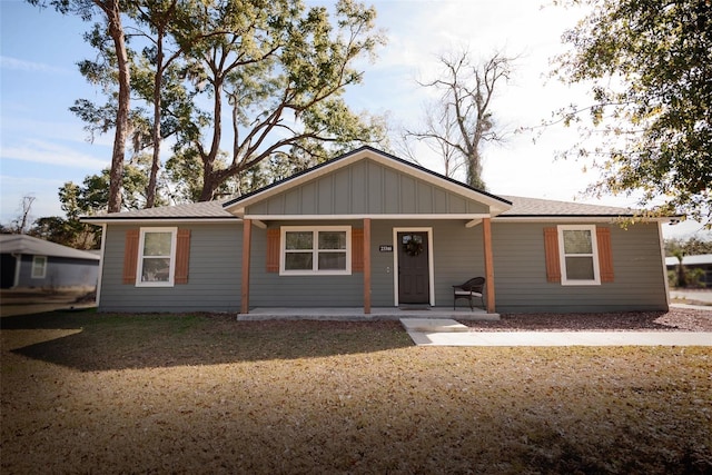 ranch-style house featuring covered porch and a front lawn