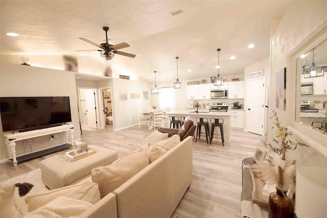 living room with ceiling fan, lofted ceiling, and light wood-type flooring