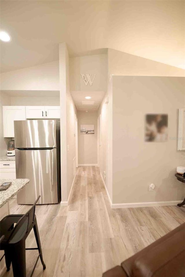 hallway featuring vaulted ceiling and light wood-type flooring