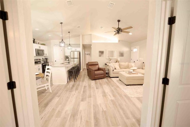 living room with ceiling fan, lofted ceiling, and light wood-type flooring