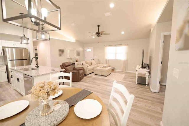 living room featuring vaulted ceiling, ceiling fan, sink, and light hardwood / wood-style flooring