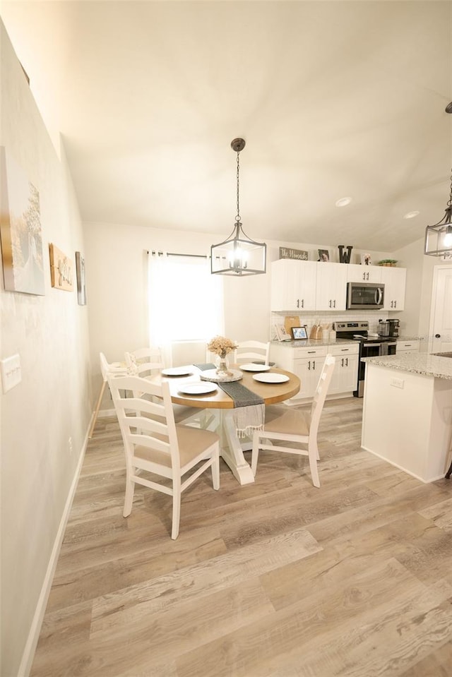 dining area featuring lofted ceiling and light wood-type flooring