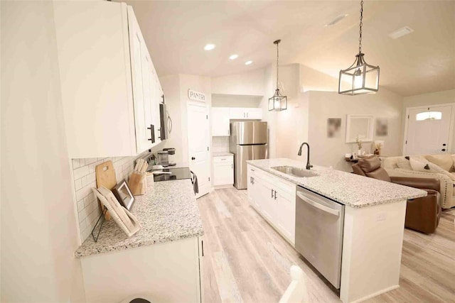 kitchen featuring sink, light hardwood / wood-style flooring, appliances with stainless steel finishes, hanging light fixtures, and white cabinets