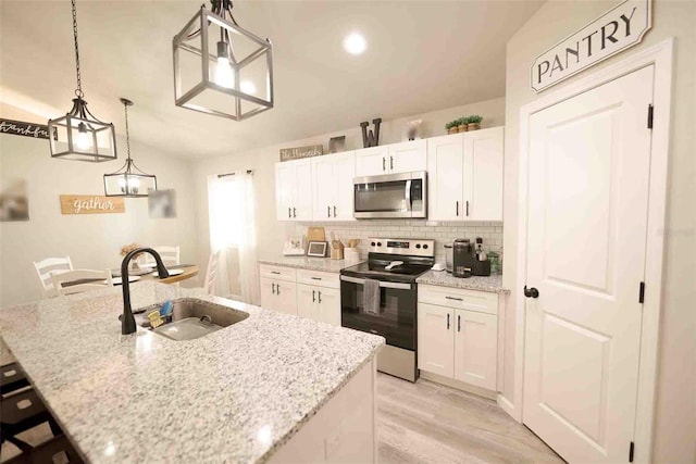 kitchen featuring appliances with stainless steel finishes, decorative light fixtures, sink, and a center island with sink