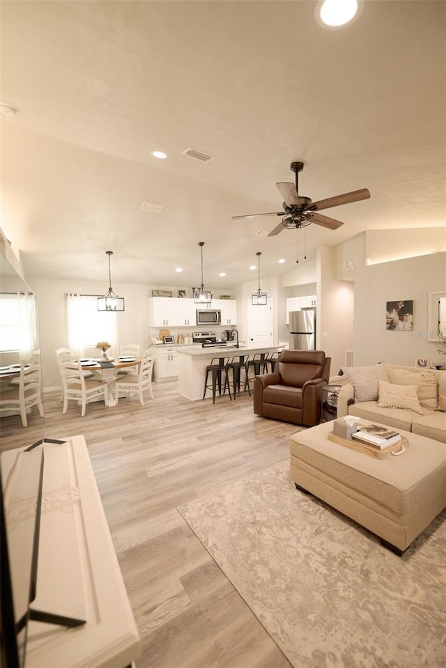 living room with lofted ceiling, light hardwood / wood-style floors, and ceiling fan