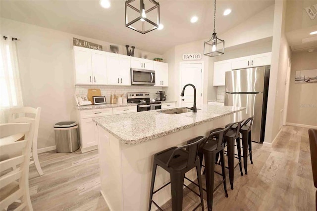 kitchen with a kitchen island with sink, sink, white cabinetry, and appliances with stainless steel finishes