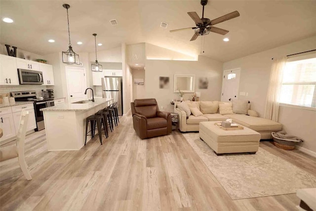 living room with lofted ceiling, sink, light hardwood / wood-style flooring, and ceiling fan