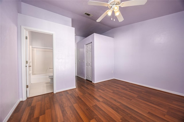 unfurnished bedroom featuring ceiling fan, lofted ceiling, dark wood-type flooring, and ensuite bath