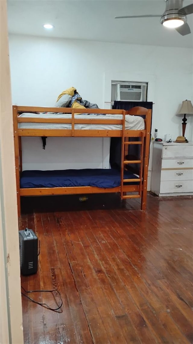 unfurnished bedroom with ceiling fan, dark wood-type flooring, and a wall mounted AC