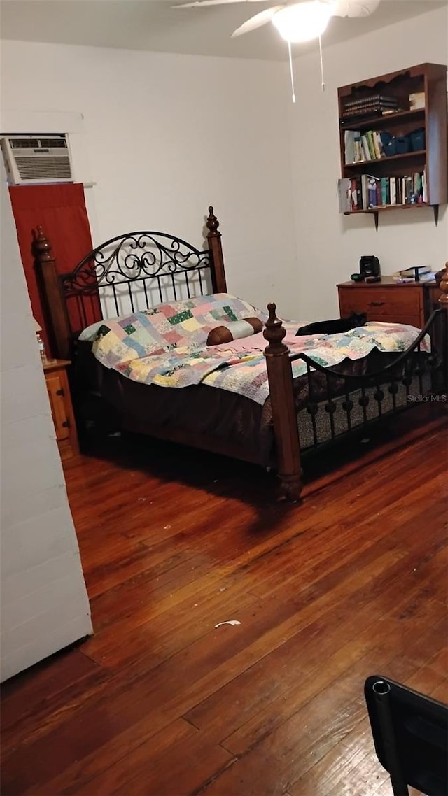 bedroom with a wall mounted air conditioner, dark wood-type flooring, and ceiling fan