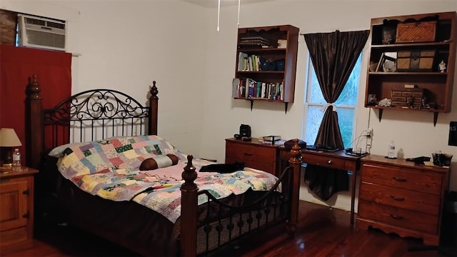 bedroom with dark hardwood / wood-style floors and a wall unit AC