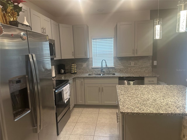 kitchen with sink, hanging light fixtures, stainless steel appliances, light stone counters, and decorative backsplash