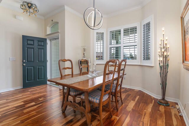 dining room with dark wood-type flooring, crown molding, and a chandelier