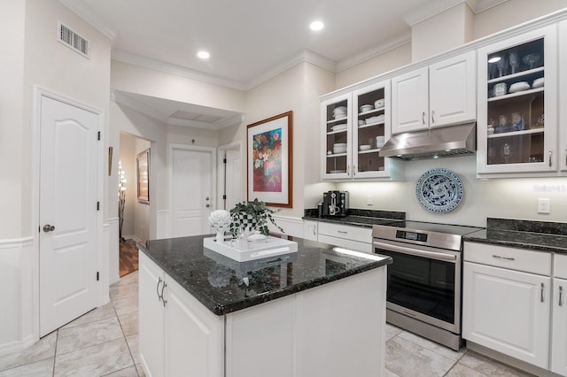 kitchen with ornamental molding, a kitchen island, dark stone counters, stainless steel electric stove, and white cabinets