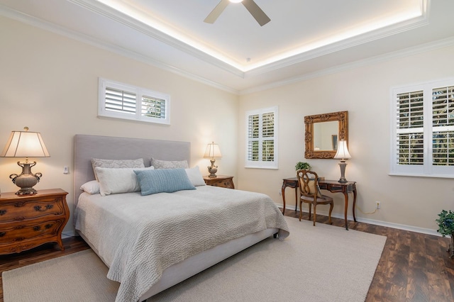 bedroom with dark hardwood / wood-style floors, ornamental molding, a tray ceiling, and multiple windows