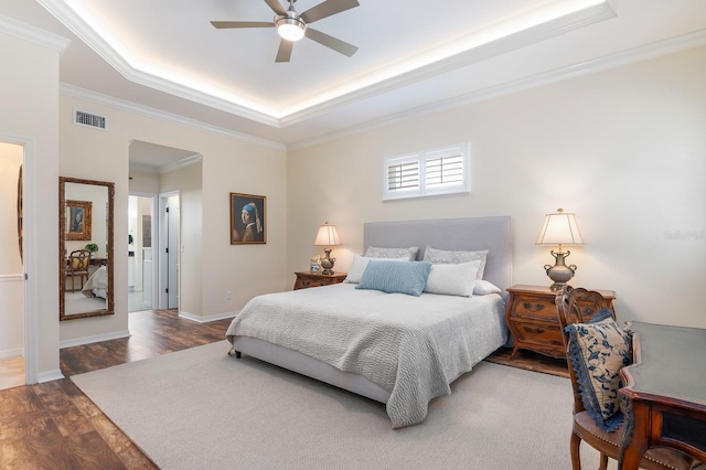 bedroom featuring hardwood / wood-style flooring, ceiling fan, a tray ceiling, and crown molding