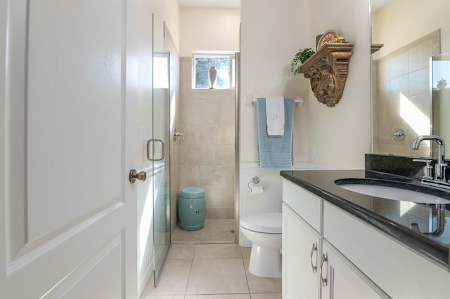 bathroom with tile patterned floors, toilet, a shower with shower door, tile walls, and vanity