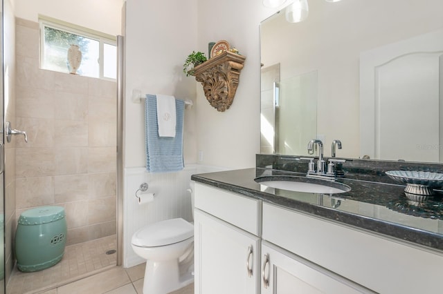 bathroom featuring tile patterned flooring, vanity, a shower with shower door, and toilet