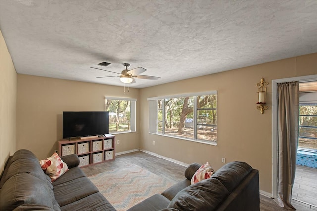 carpeted living room featuring ceiling fan and a textured ceiling