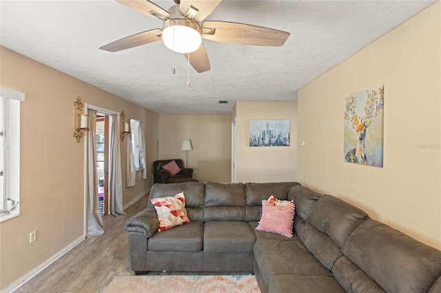 living room featuring ceiling fan, light hardwood / wood-style floors, and a textured ceiling