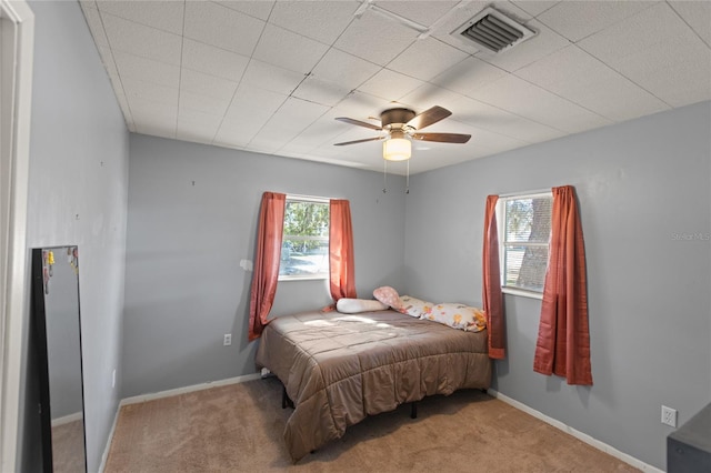 carpeted bedroom with multiple windows and ceiling fan