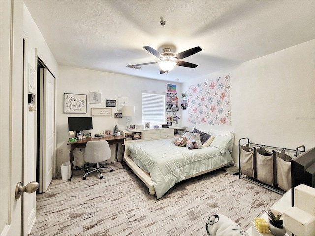 bedroom with a closet, ceiling fan, light hardwood / wood-style floors, and a textured ceiling