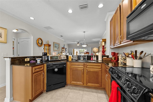 kitchen featuring crown molding, light tile patterned floors, kitchen peninsula, dark stone counters, and black appliances