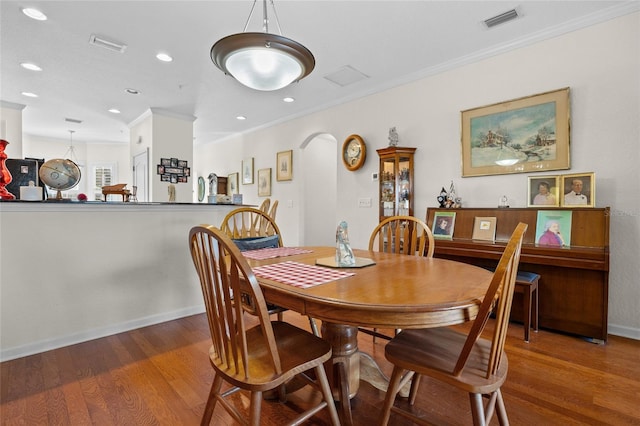 dining space featuring dark wood-type flooring and crown molding