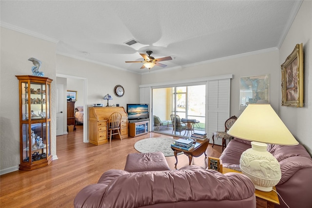 living room with ceiling fan, crown molding, light hardwood / wood-style flooring, and a textured ceiling