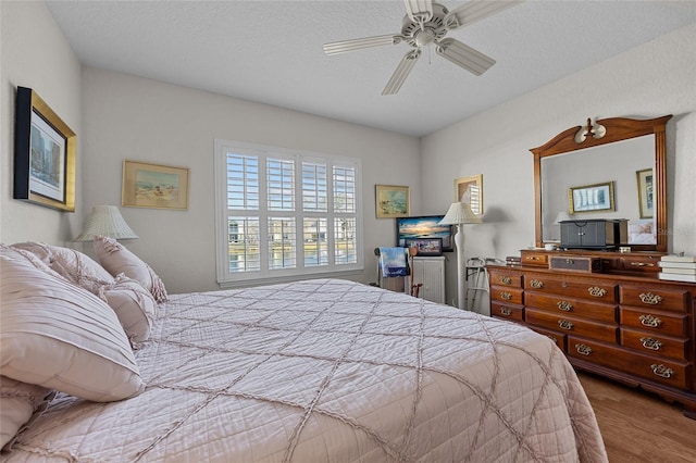 bedroom with hardwood / wood-style flooring, ceiling fan, and a textured ceiling