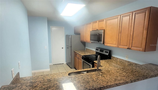 kitchen featuring sink, light tile patterned floors, appliances with stainless steel finishes, kitchen peninsula, and dark stone counters